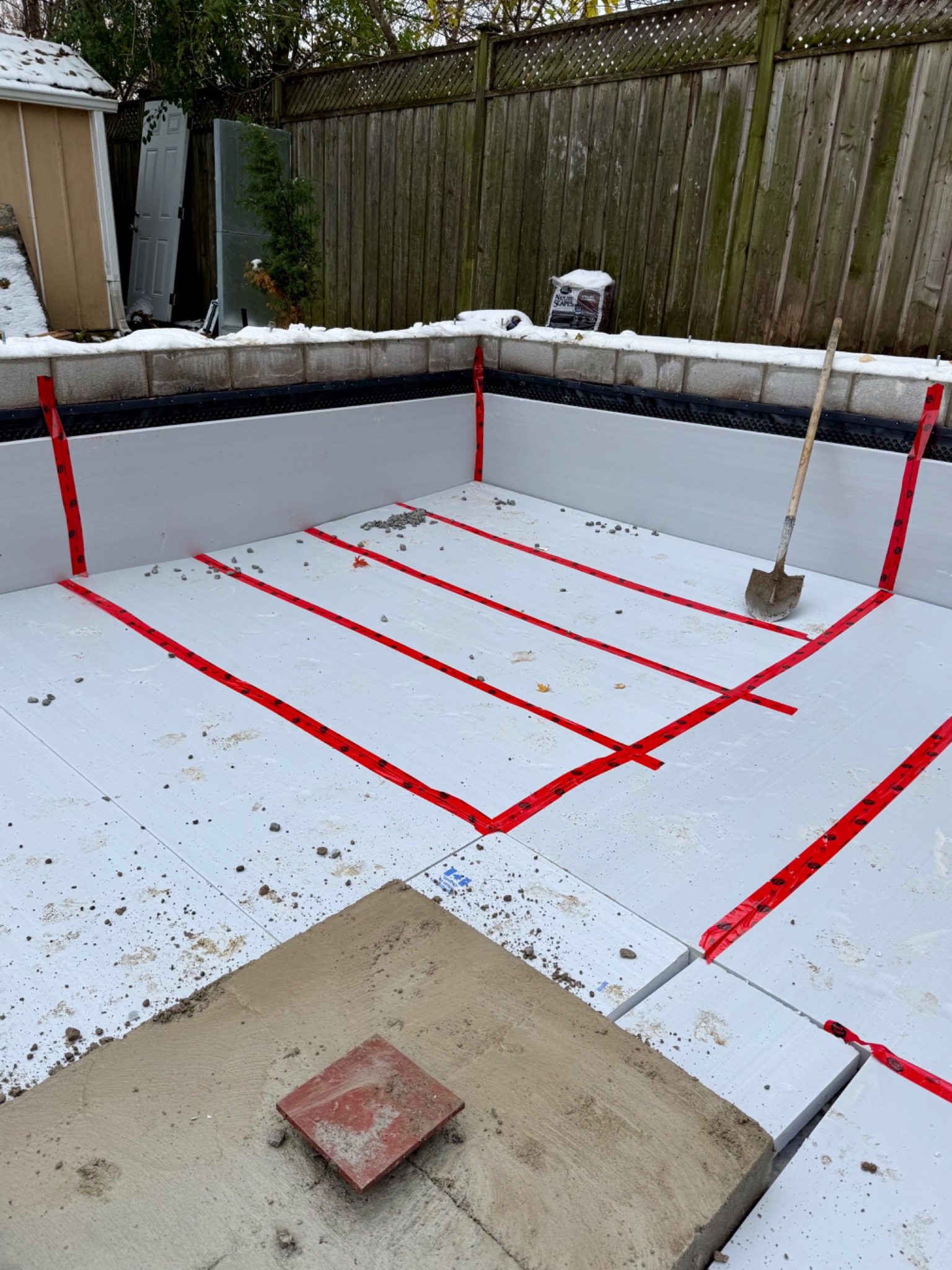 Rigid insulation boards with sealed joints across the floor and foundation-wall interior