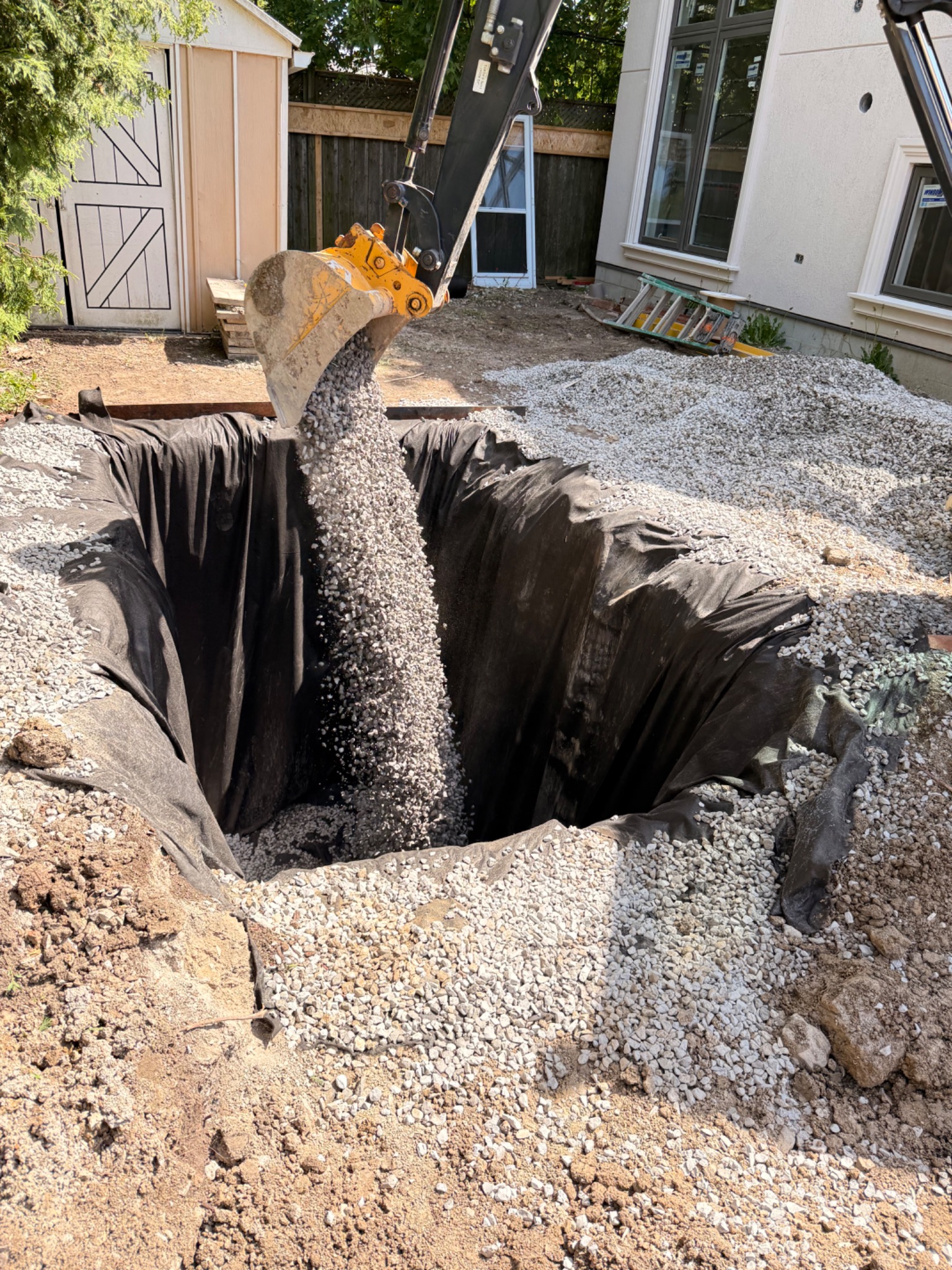 Clear stone being placed into a geotextile-lined drainage zone
