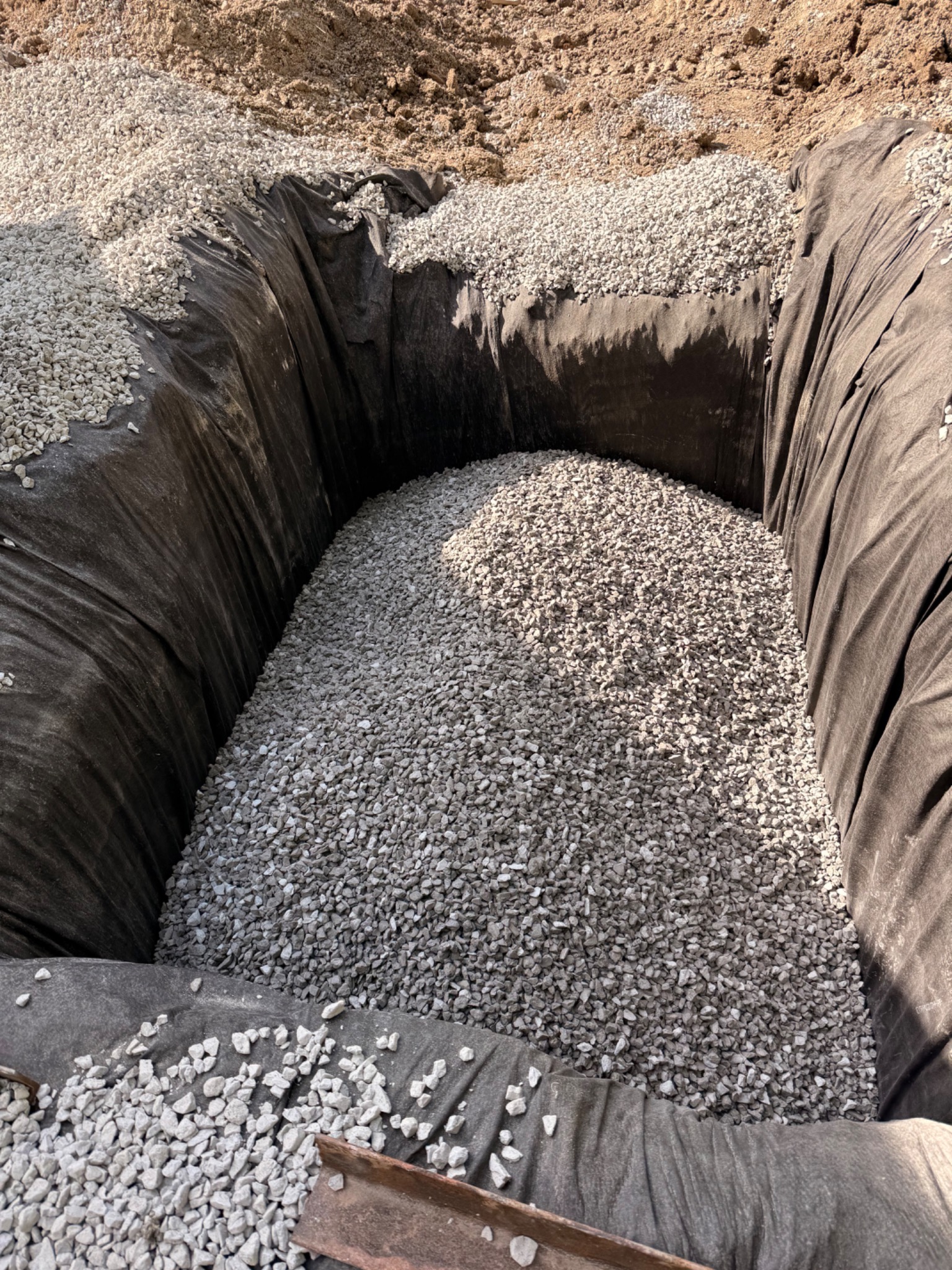 Clear stone placed within a geotextile-lined drainage excavation