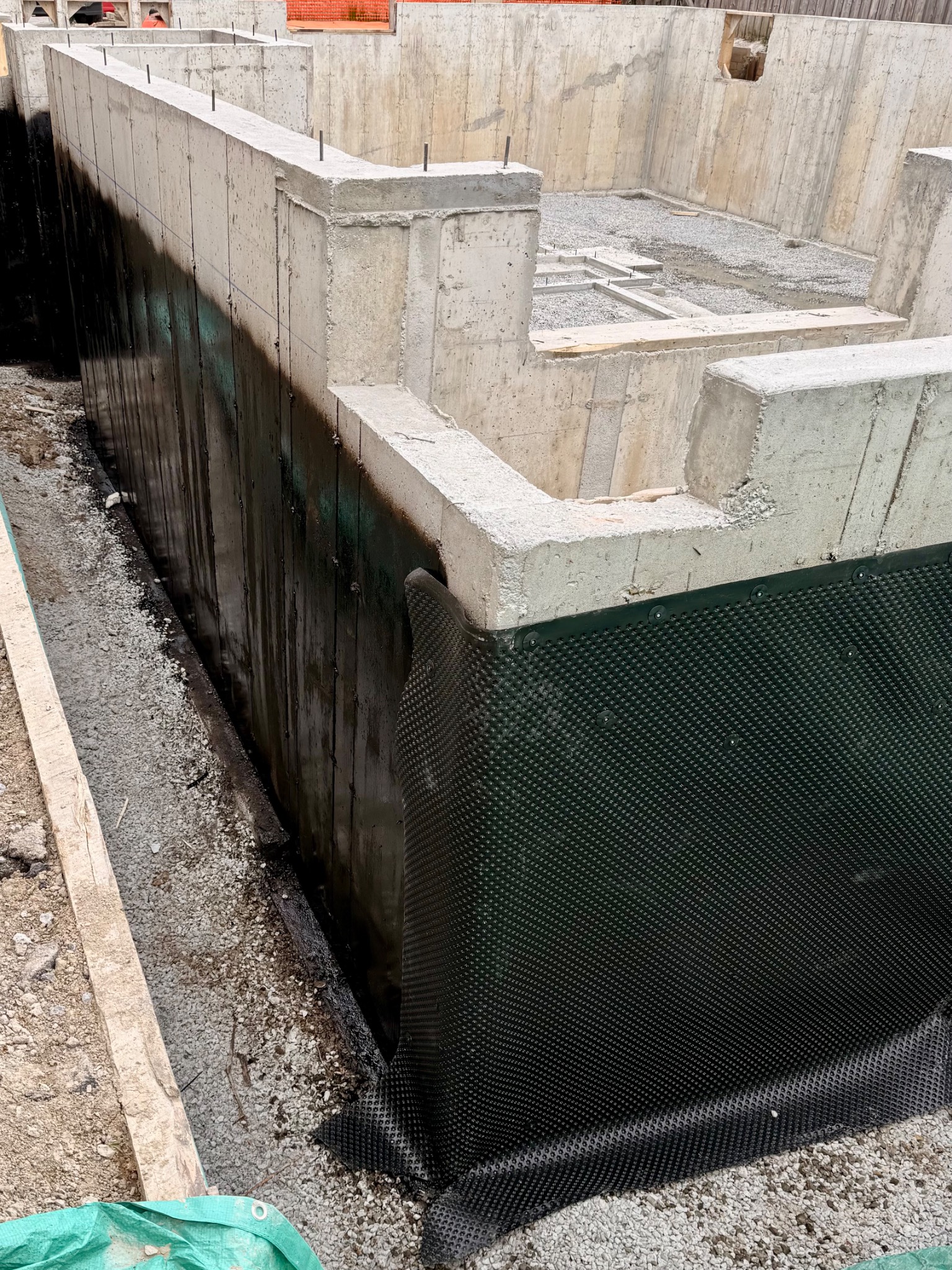 Layered foundation coating and drainage membrane at below-grade concrete walls